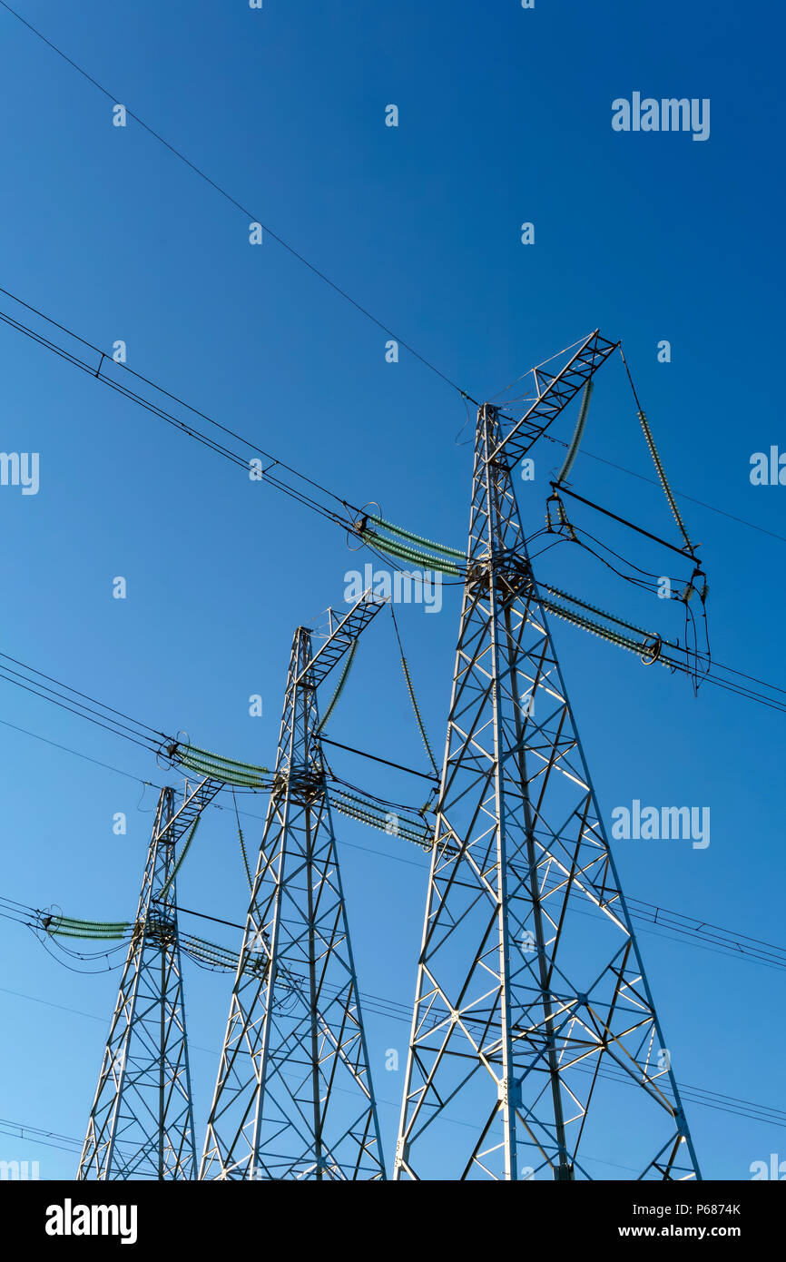 Tre power line tralicci contro un cielo blu sullo sfondo Foto Stock