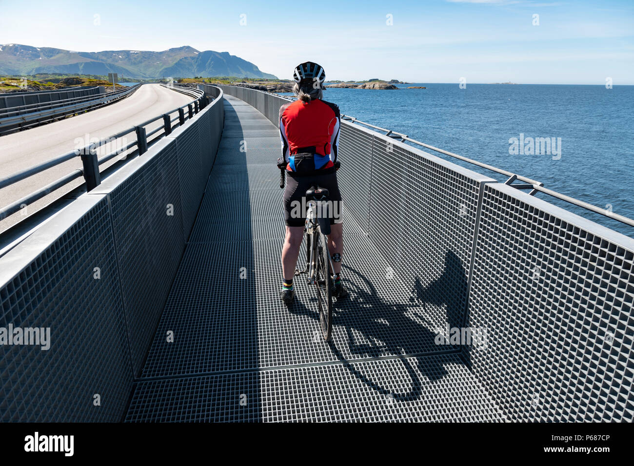 Ciclista femmina sull'Atlantico Road causeway, Norvegia. Foto Stock