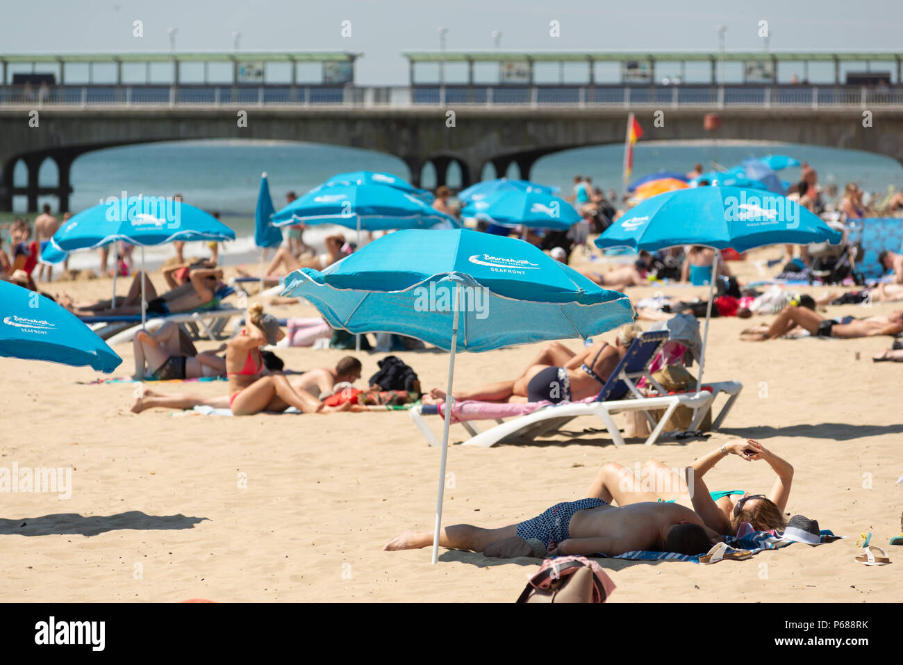 2018 ondata di caldo; la gente a prendere il sole sulla spiaggia a prendere il sole nel tempo caldo vicino al molo a Boscombe, Bournemouth Dorset, Regno Unito Foto Stock