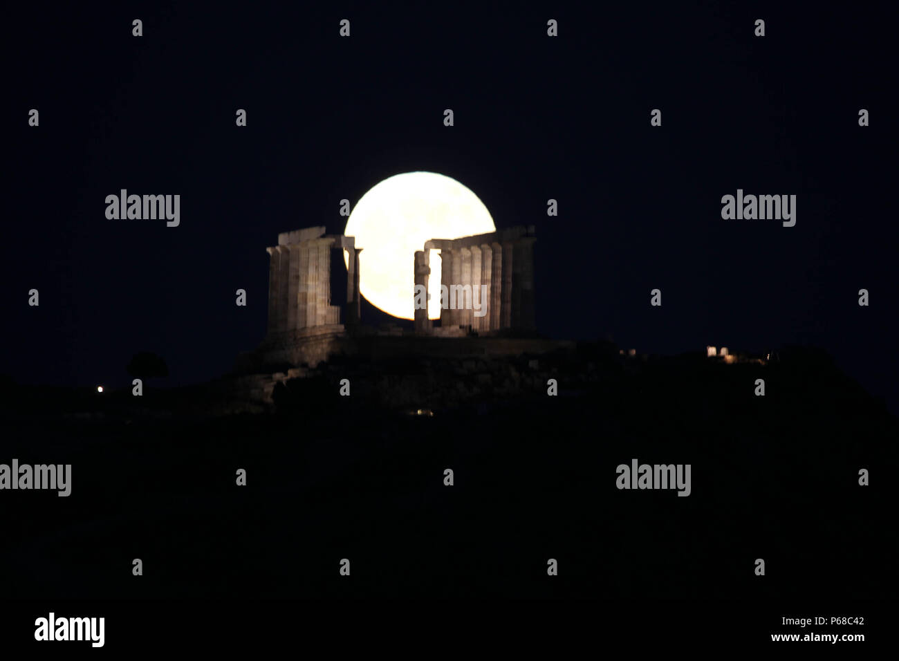 Atene, Grecia. Il 28 giugno, 2018. La luna piena sorge dietro le colonne di marmo antico tempio di Poseidone a Capo Sounion, circa 70 Km (45 miglia) a sud-sud-est di Atene. Il tempio si trova su un promontorio di Capo Sounion, costruito 444 a.c. e dedicato a Poseidone, il dio del mare. Credito: Aristidis Vafeiadakis/ZUMA filo/Alamy Live News Foto Stock