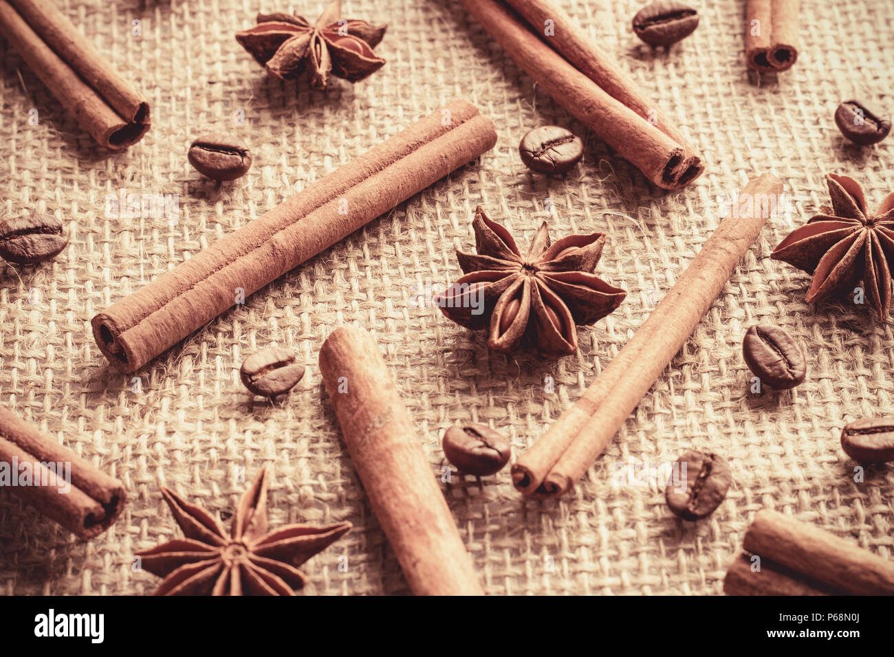 I chicchi di caffè e bastoncini di cannella con anice stelle sono organizzati separatamente su un letto di sacco sullo sfondo Foto Stock