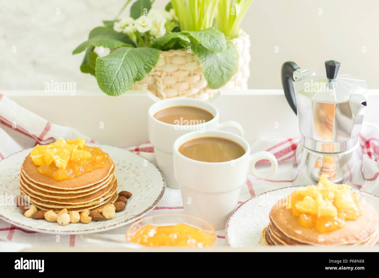 Colazione perfetta per 2. Vassoio con frittelle con marmellata di arancia e i dadi sulle piastre di vintage e 2 bianco tazze di caffè Foto Stock