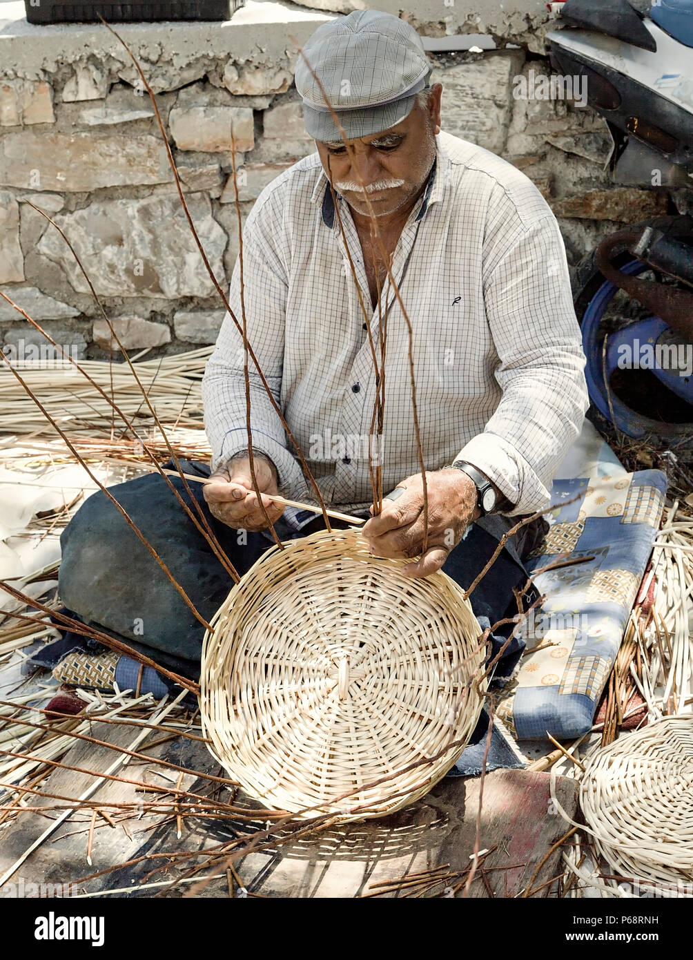 Ermoupolis: Giugno 28. Maschio Zingaro greco tessitura cesti fatti a mano dal lato della strada. Ermoupolis, Syros 28 Giugno 2018. La Grecia. Foto Stock
