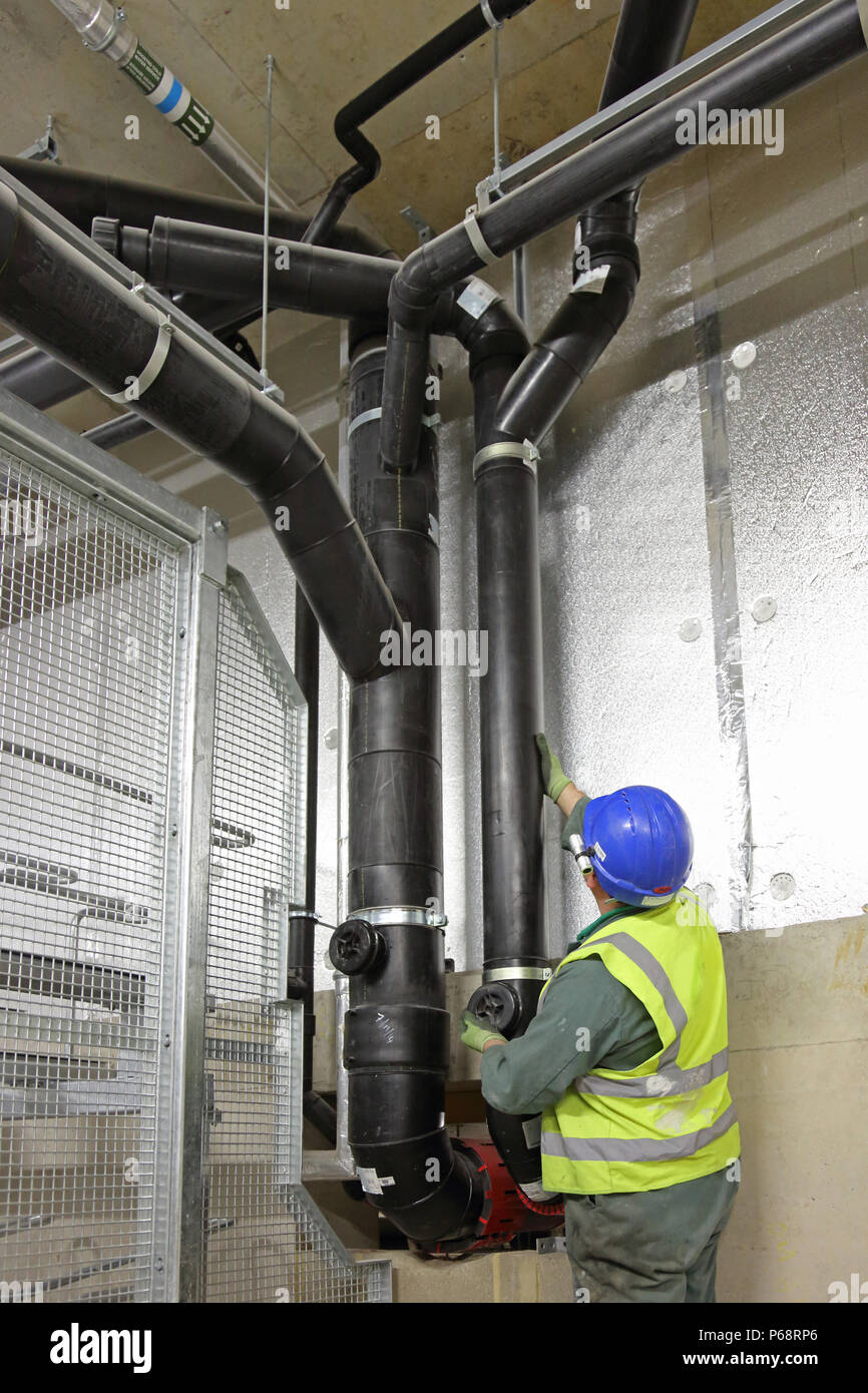 Un ingegnere di pressione-prove di una nuova installazione di drenaggio nel seminterrato di una nuova torre residenziale blocco in Londra, Regno Unito Foto Stock