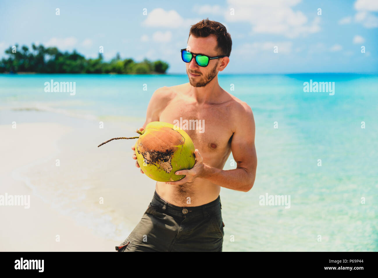 Giovane uomo bello in occhiali da sole in spiaggia Foto Stock