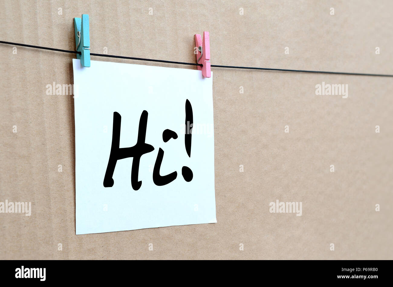 Ciao! Nota è scritta su un adesivo bianco che si blocca con un clothespin su una fune su uno sfondo di cartone marrone . Foto Stock