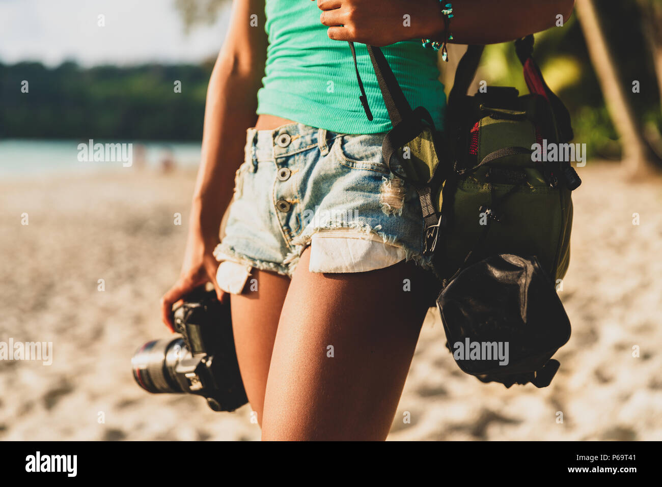 Giovane donna felice con la fotocamera in mano sulla spiaggia tropicale al tramonto, vacanze estive e concetto di stile di vita Foto Stock