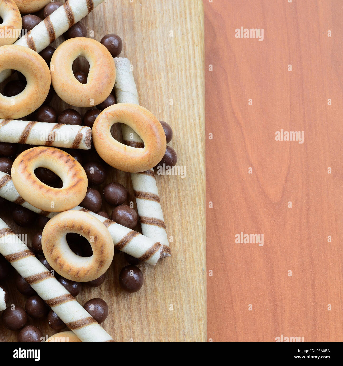 Croccante di tubuli, cioccolato palline di fusione e bagel giacciono su una superficie in legno. Mix di vari dolci . Foto Stock