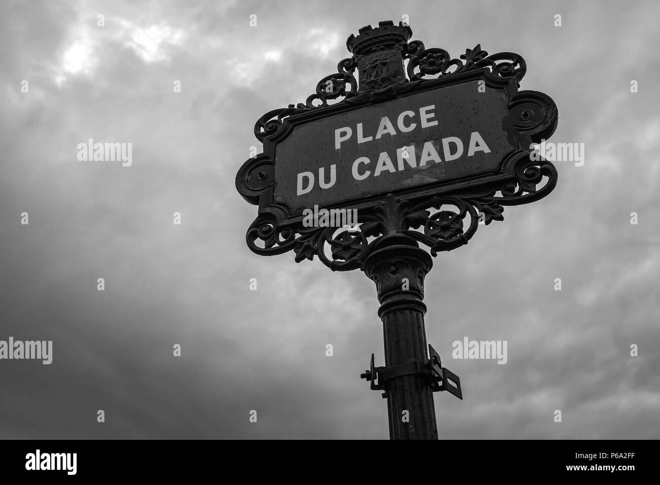 Parigi, Francia - 4 Novembre 2016: Place du Canada Parigino tradizionale targa montata sul ferro battuto signpost. In bianco e nero dai toni vintage foto Foto Stock