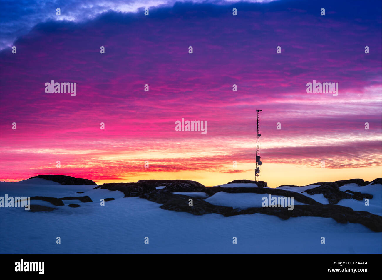 Groenlandese Cielo di tramonto con antenna e rocce con neve in primo piano, Nuuk, Groenlandia Foto Stock