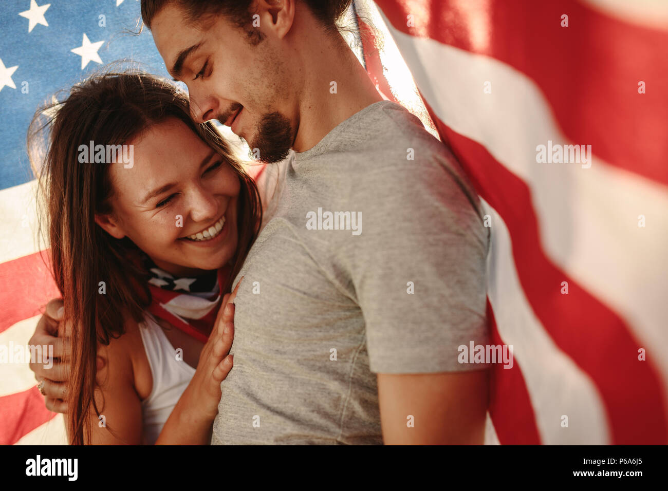 Matura in amore con la bandiera americana intorno a. Felice giovane uomo e donna sotto USA bandiera nazionale. Foto Stock