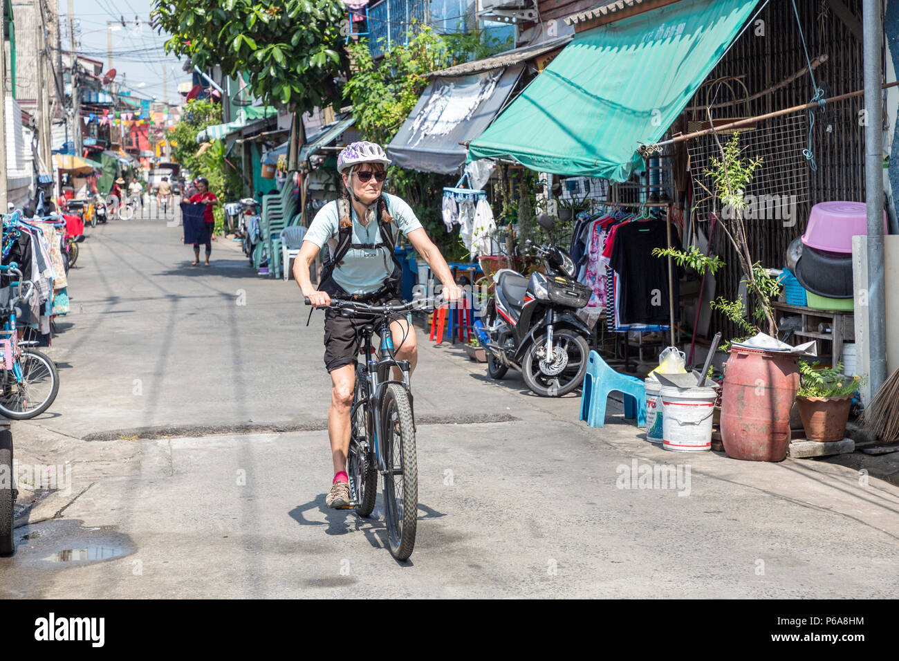 Donna in bicicletta attraverso vicoli a Bangkok, in Thailandia Foto Stock