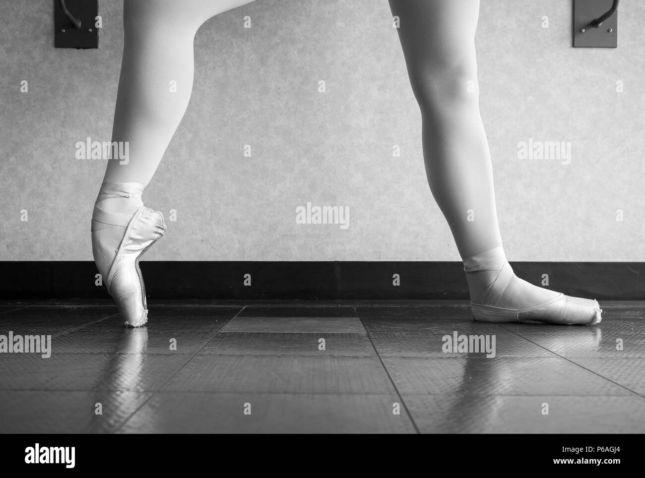 Versione in bianco e nero della ballerina in classe di balletto in fase di riscaldamento ha pointe shoes, balletto pantofole a barre Foto Stock