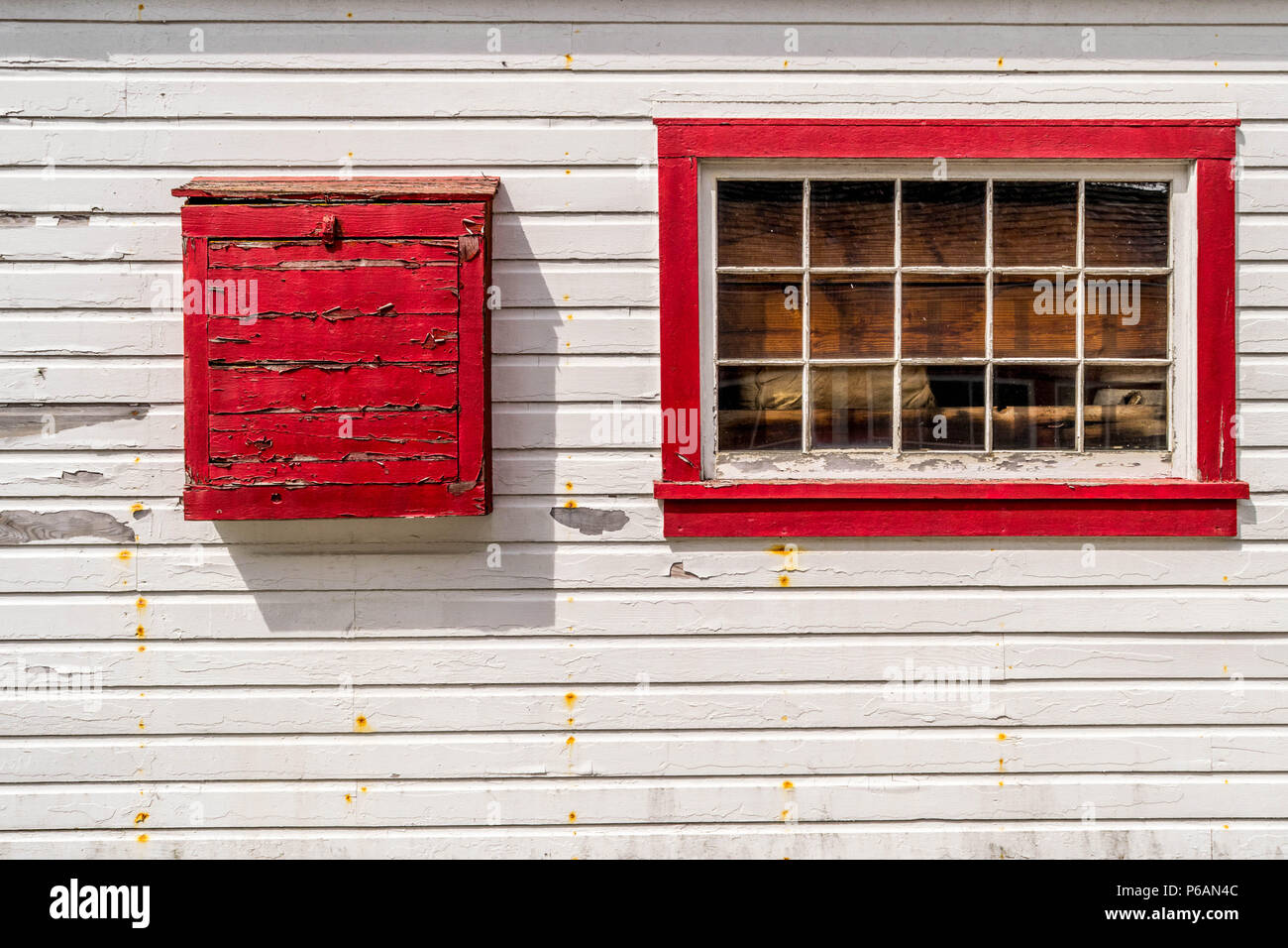 Abbandonato edificio bianco con red finestra incorniciata e vernice di pelatura Foto Stock