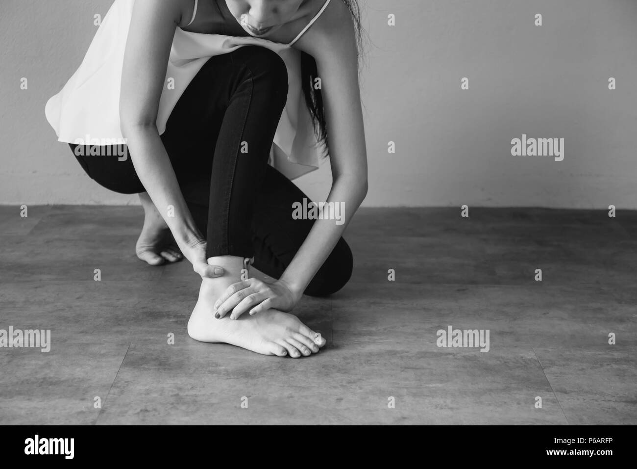 Giovane donna avente il dolore della caviglia in bianco e nero il tono - sanitari e medici concetto Foto Stock