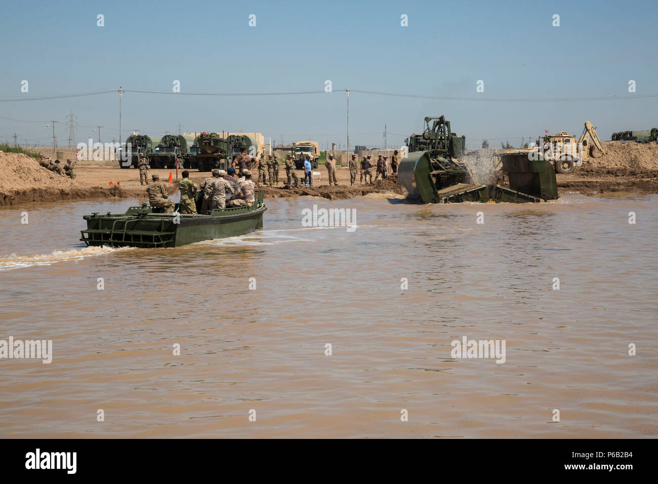 Stati Uniti Gli ingegneri dell'esercito, assegnato all'502nd multiruolo società Ponte, ingegnere xix Battaglione, e soldati iracheni con l'esercito iracheno reggimento di Bridging, osservare come un ponte galleggiante viene impiegato sul acqua a Camp Taji, Iraq, 21 aprile 2016. Il 502nd multiruolo Bridge azienda distribuisce in tutto il mondo per eseguire a livello strategico il supporto logistico ad un teatro di operazioni di apertura e di mantenimento di critici di linee di comunicazione attraverso infrastrutture di bridging e conducendo fisso e ponte galleggiante operazioni. Abilitando le forze di sicurezza irachene attraverso la consulenza e assistenza e la costruzione di capacità del partner m Foto Stock