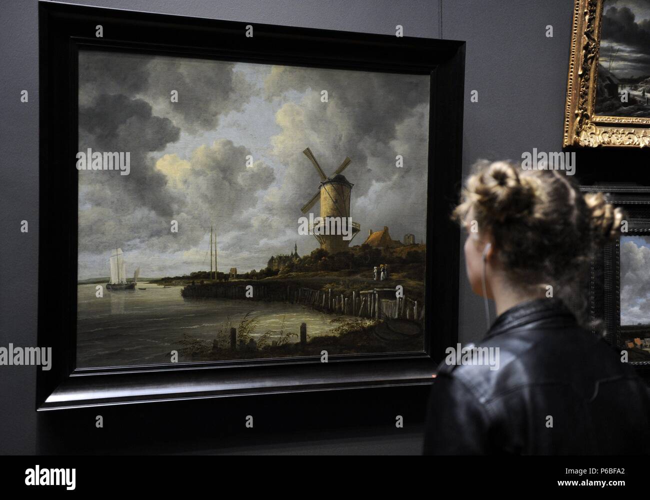 Ragazza guardando un dipinto. Il mulino a vento a Wijk bij Duurstede 1670 da Jacob Ruysdael (1628-1682). Rijksmuseum. Amsterdam. Paesi Bassi. Foto Stock