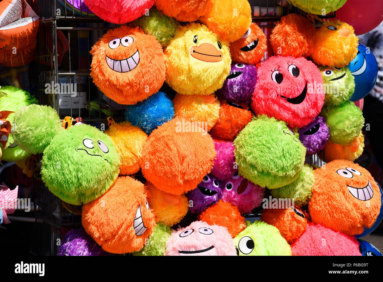 Luminosa, colorata, colorato, sorridente sorridente lussureggiante giocattoli su un mare di stallo di souvenir shop. Southend on Sea, Essex, Regno Unito. I peluche. I giocattoli di peluche Foto Stock