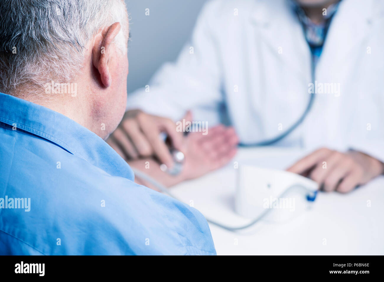 Primo piano di un medico caucasica uomo in camice bianco, con la misurazione della pressione del sangue di un senior caucasica uomo paziente con uno sfigmomanometro Foto Stock