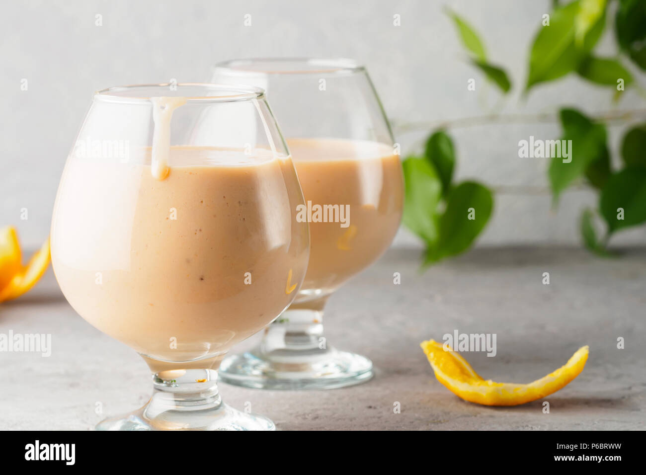 Due bicchiere da cocktail con i frullati frullato bibita salutare orange scorze di agrumi banane latte e yogurt gelato dieta sana cibo Foto Stock