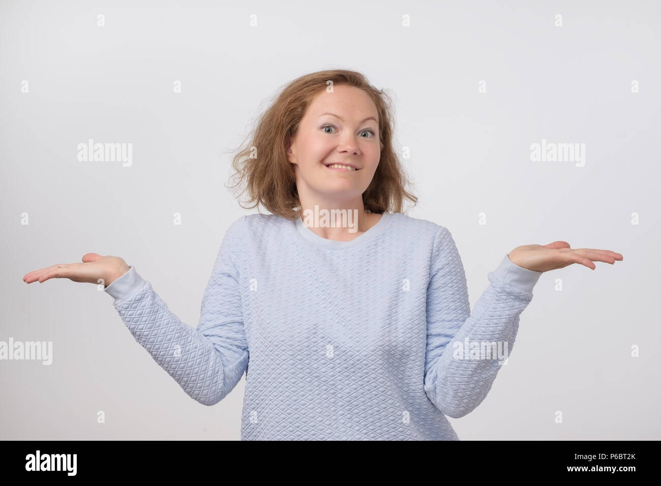 Scrollare norvegese di donna che indossa un maglione blu in caso di dubbi fare spallucce. Confusa ragazza gesti non sanno firmare su sfondo grigio Foto Stock