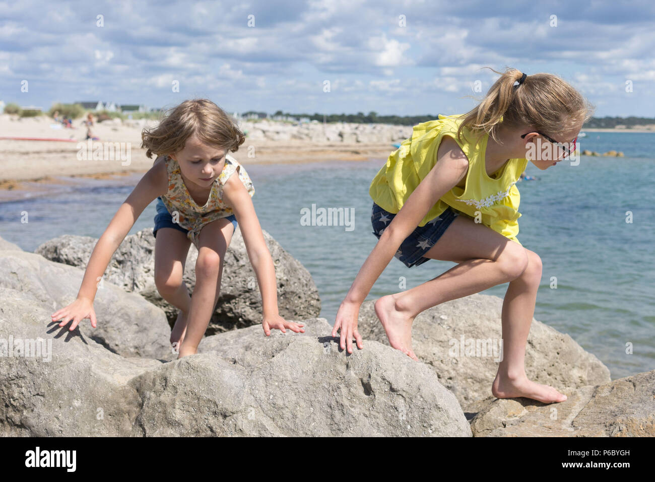 Due bambini di arrampicata su roccia in riva al mare Foto Stock