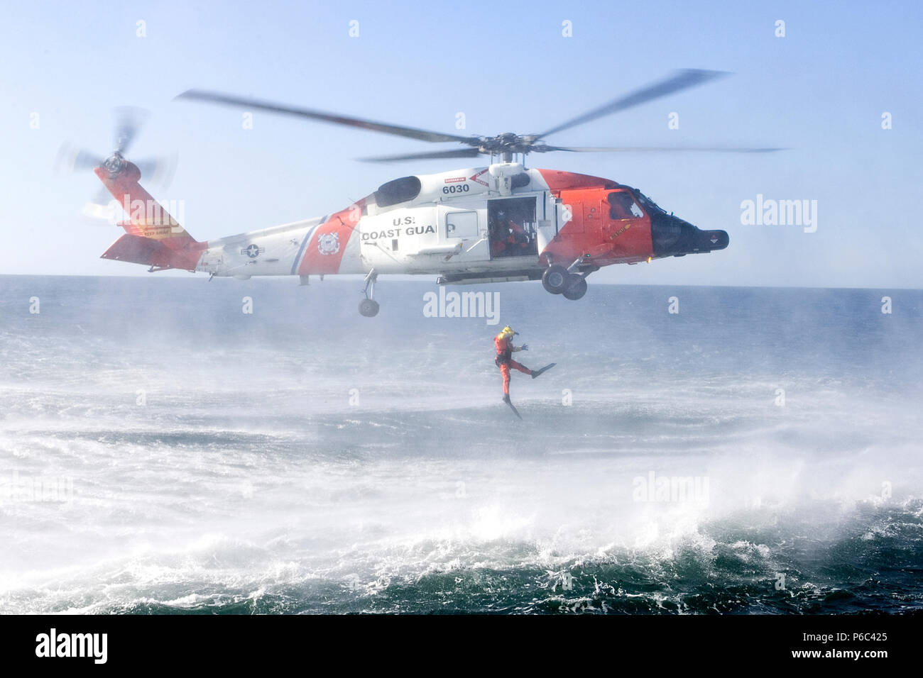 Un Coast Guard riutilizzo nuotatore distribuisce da un UH-60 elicottero nell'acqua fredda mentre la formazione sulle tecniche di recoverey in Astoria, Oregon. Foto Stock