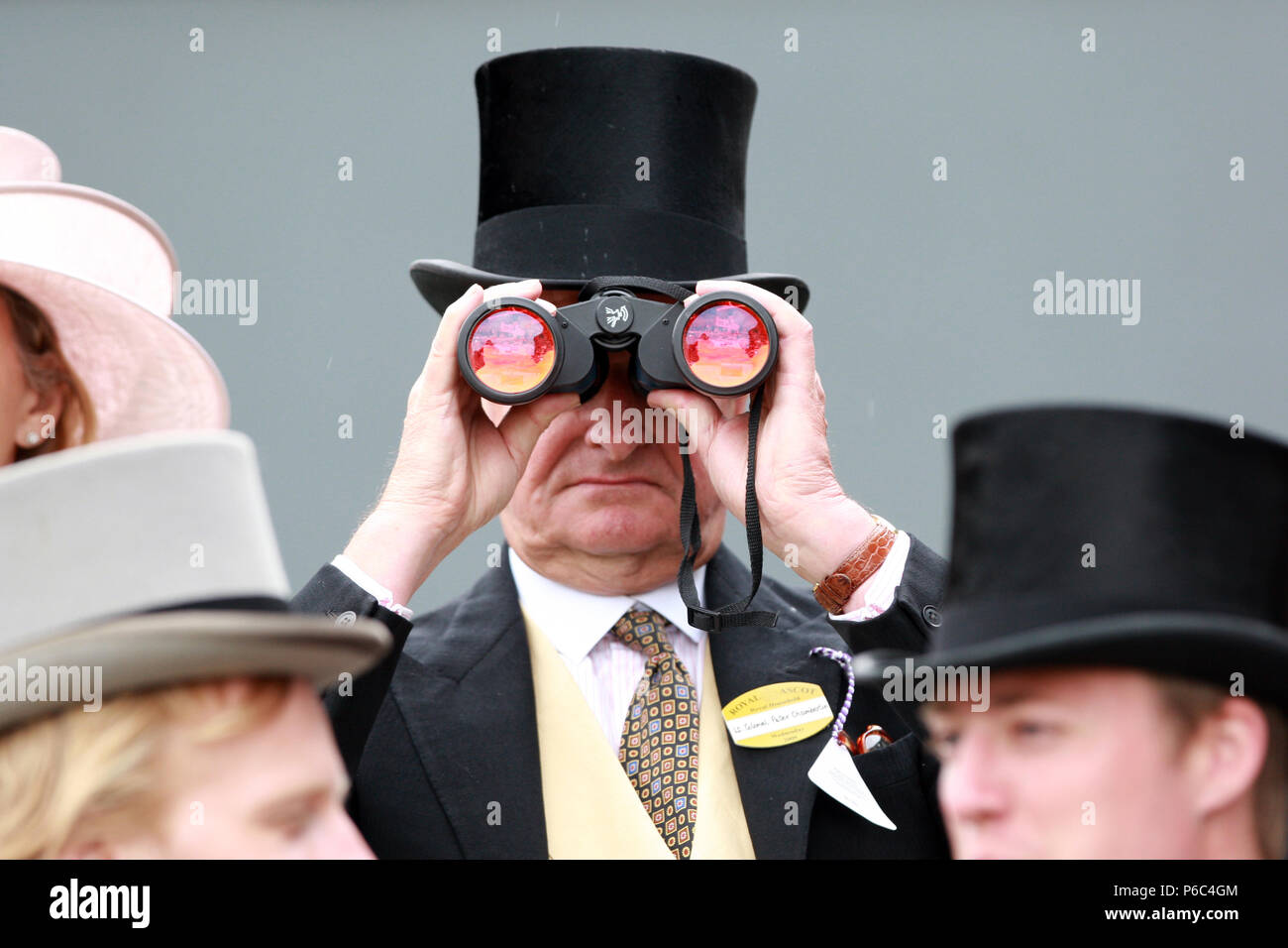 Ascot, Gran Bretagna, l'uomo con il cilindro guarda attraverso il suo binocolo Foto Stock