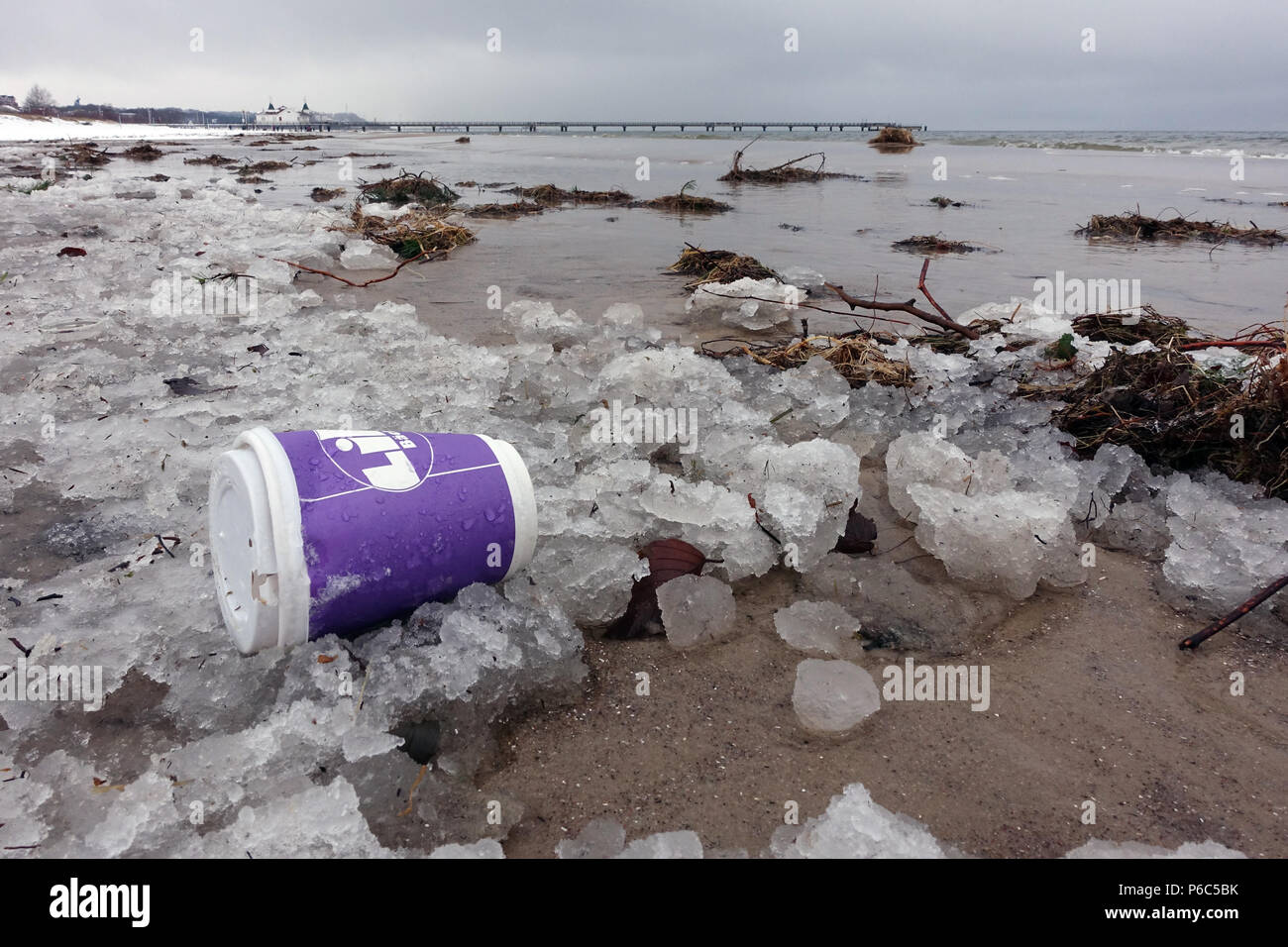 Ahlbeck, Germania, Vuoto tazza da caffè sdraiato sulla spiaggia nel ghiaccio Foto Stock