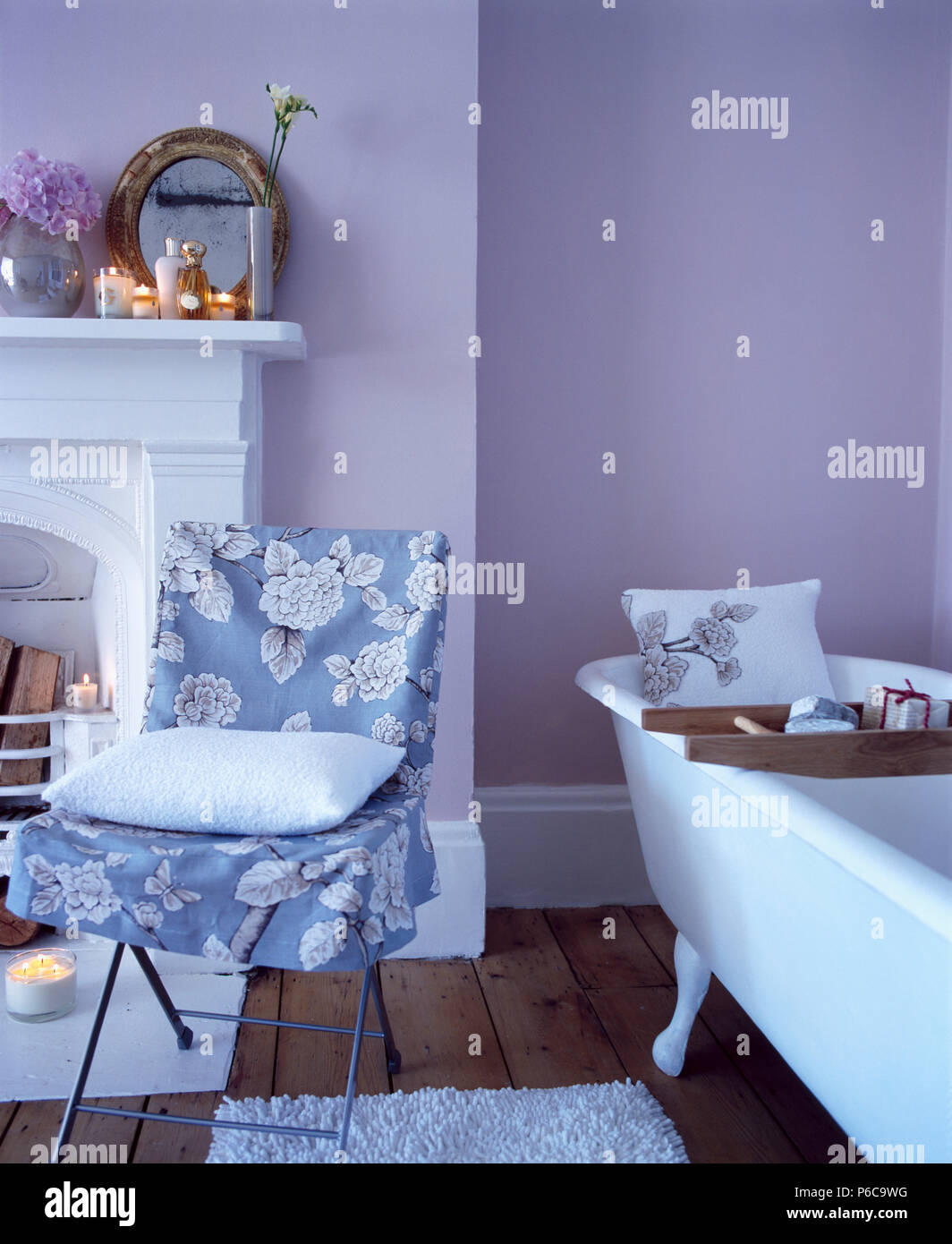 Blue+white floral loose-coperchio sulla sedia accanto a roll-top bagno in blu pallido bagno Foto Stock
