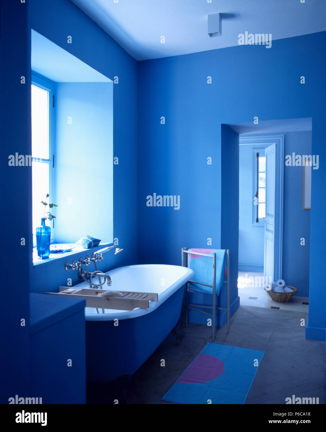 Bianco Freestanding rolltop bagno in blu cobalto bagno con asciugamani accanto a porta aperta Foto Stock