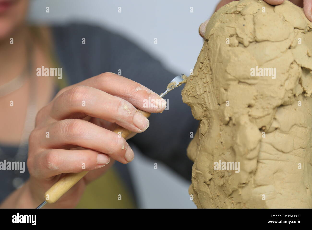 Artista scultore creando un busto scultura con argilla. È felice della sua opera, lei è concentrata, ella è scolpire una donna Foto Stock