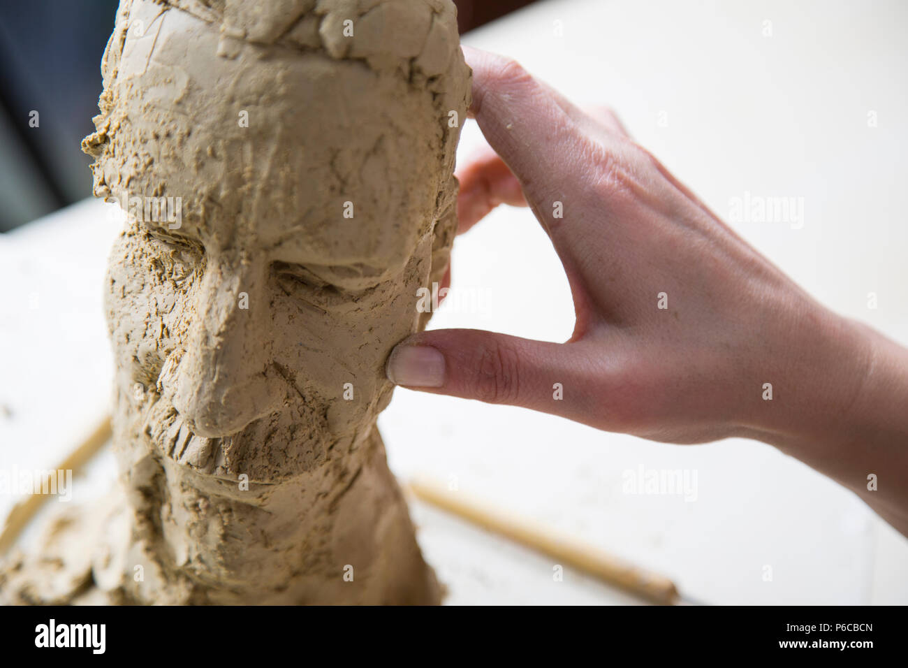 Artista scultore creando un busto scultura con argilla. È felice della sua opera, lei è concentrata, ella è scolpire una donna. Foto Stock