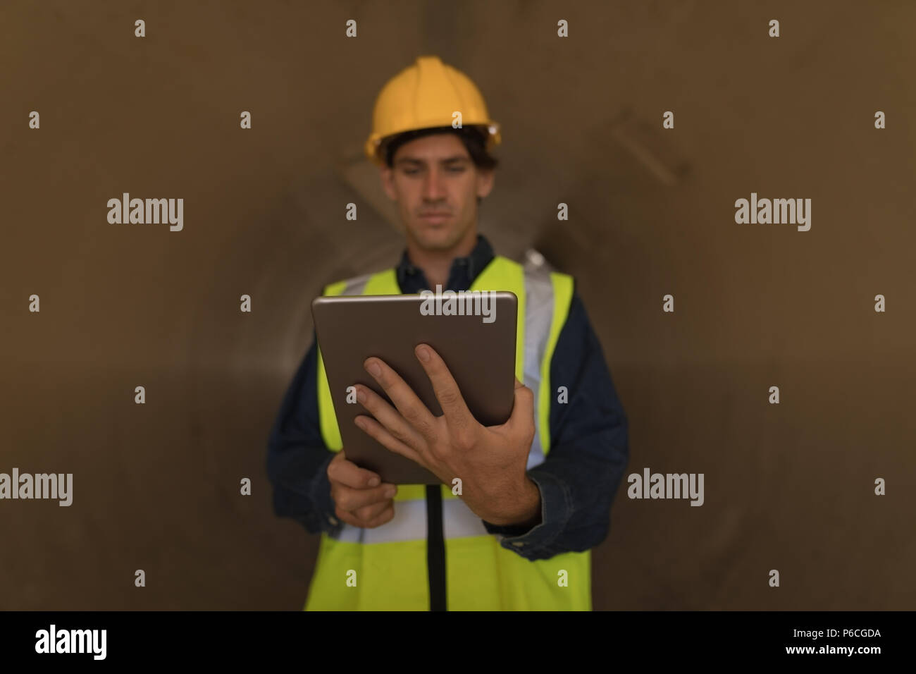 Lavoratore di sesso maschile con tavoletta digitale all'interno di un tunnel in calcestruzzo Foto Stock