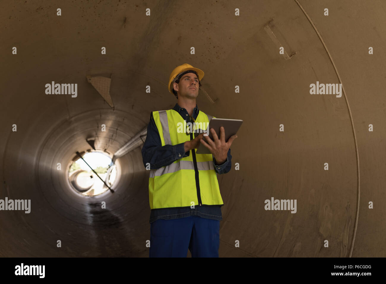 Lavoratore di sesso maschile con tavoletta digitale mentre esaminando un tunnel in calcestruzzo Foto Stock