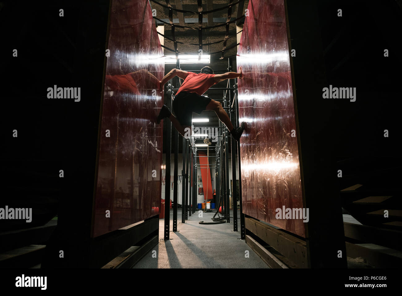 Uomo muscolare arrampicarsi tra due pareti Foto Stock