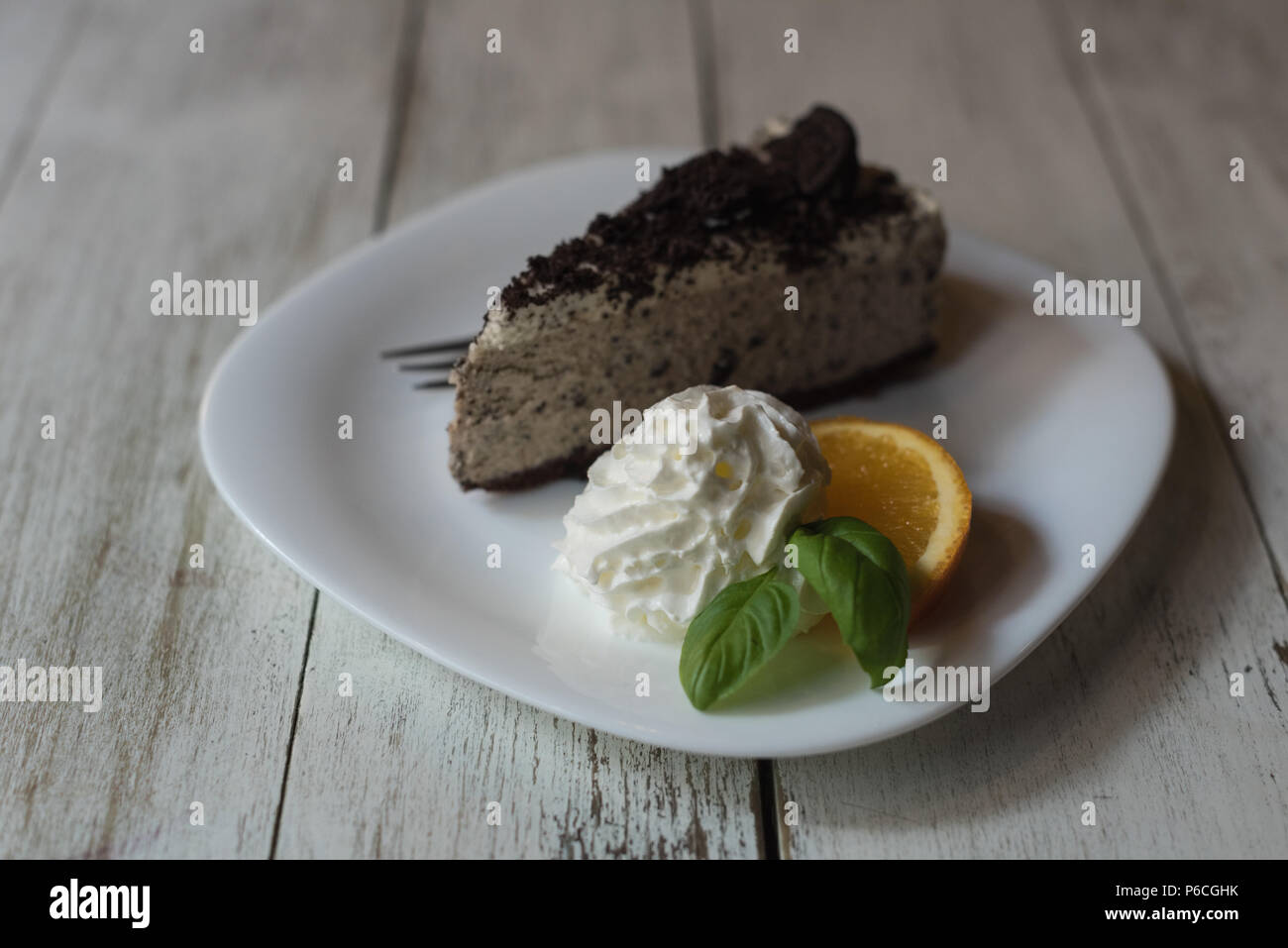 Deliziosa torta con panna montata, fetta di limone e menta nella piastra Foto Stock