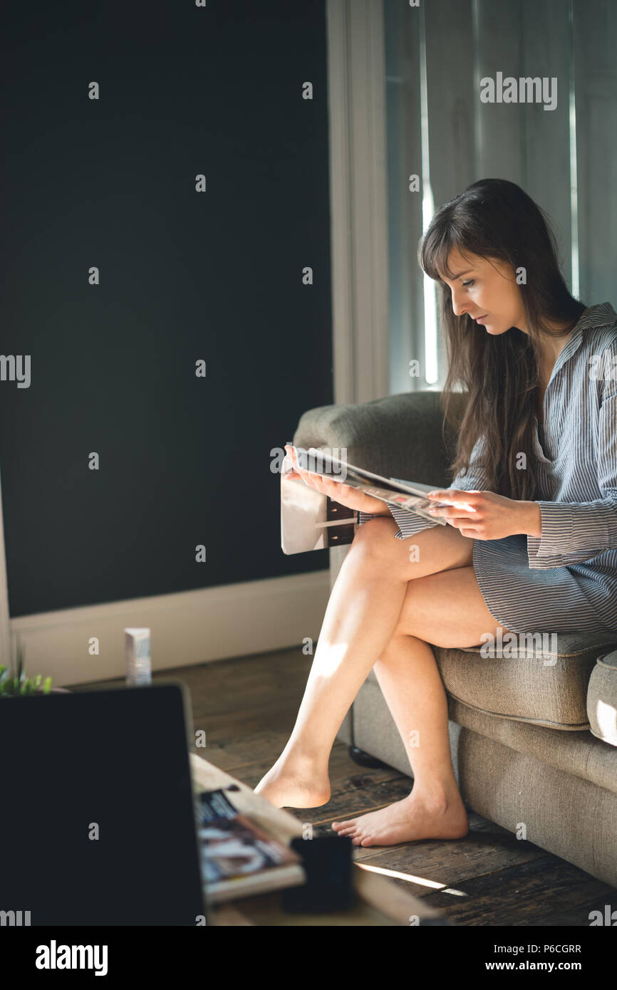 Donna rivista di lettura nel soggiorno Foto Stock