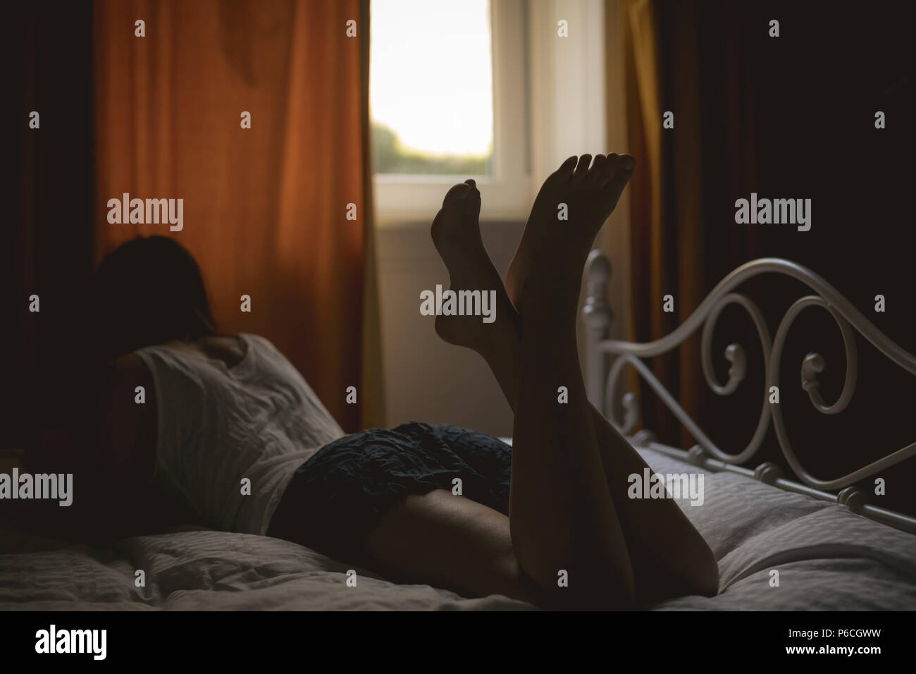 Donna sdraiata sul letto di casa Foto Stock