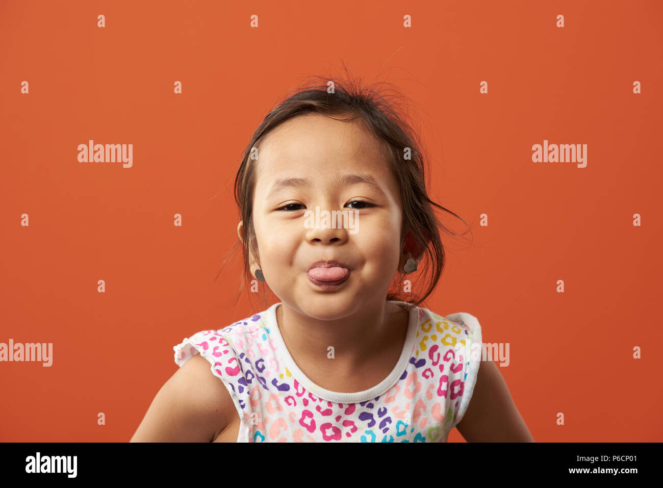 Ragazza asiatica mostra la linguetta. Divertente ritratto della piccola ragazza asiatica Foto Stock