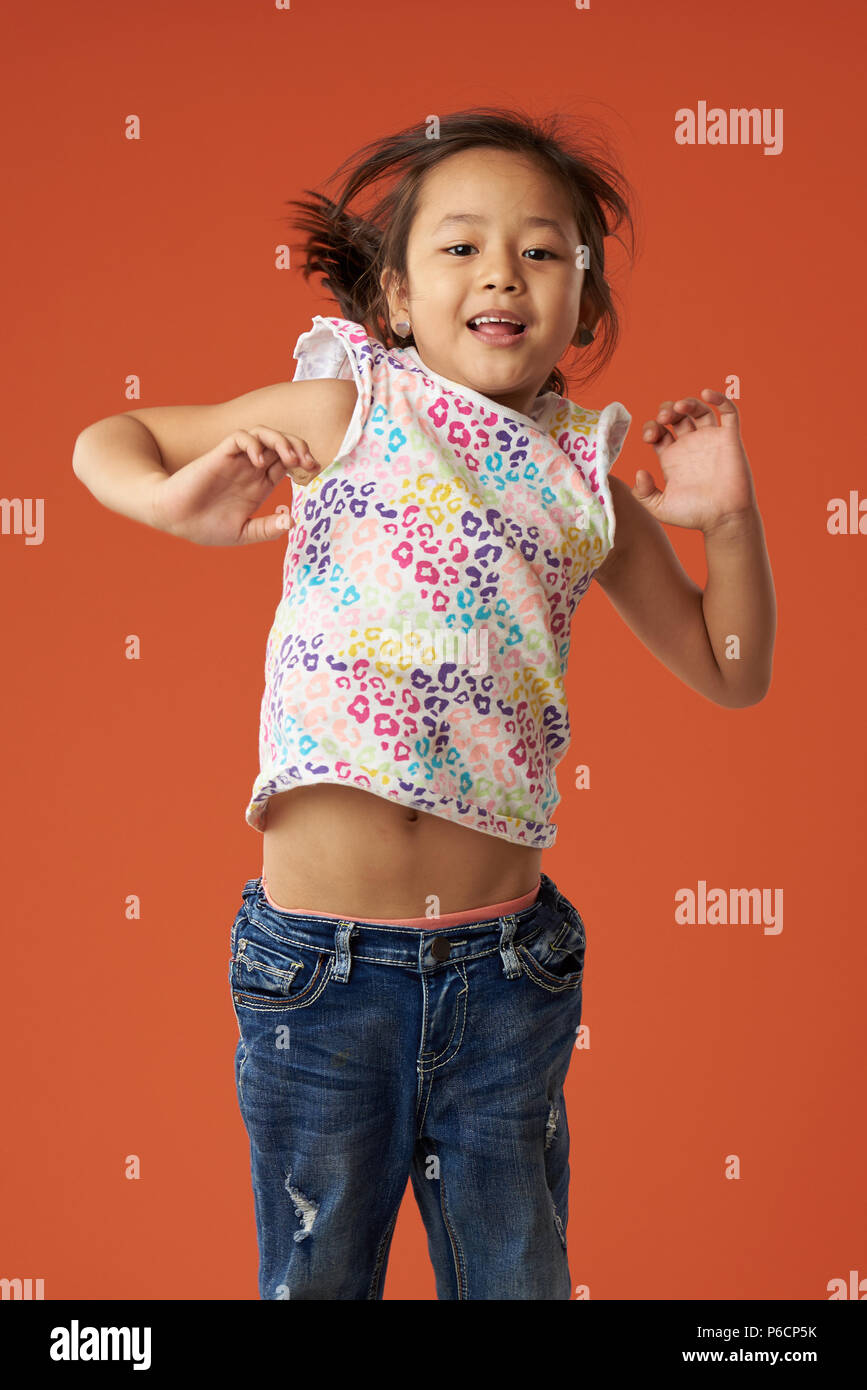 Happy jumping ragazza asiatica su orange Colore sfondo isolato Foto Stock