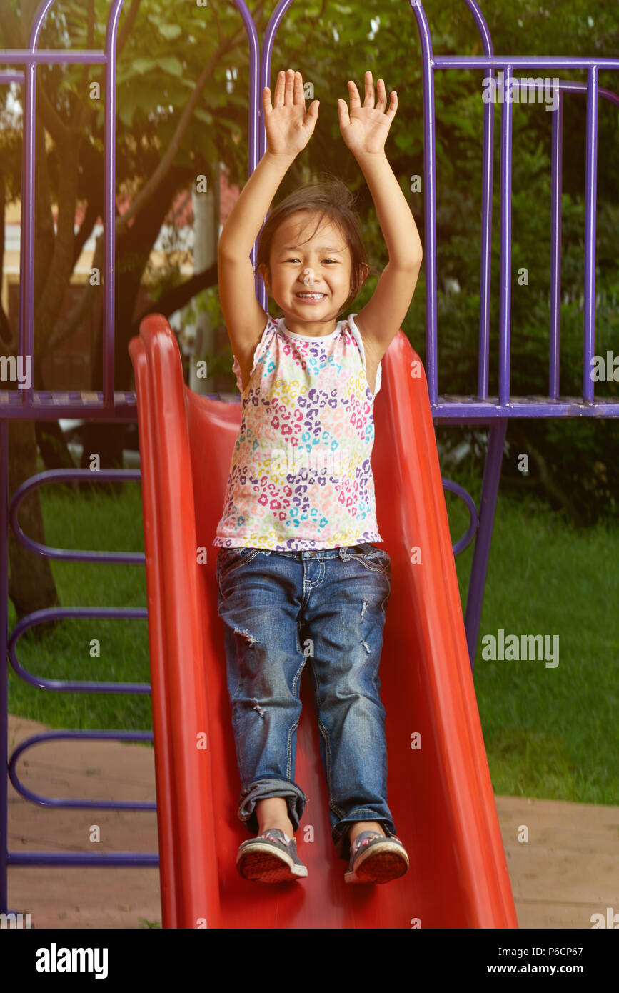 Felice ragazza nel parco diapositiva . Asian bambina nel parco giochi Foto Stock