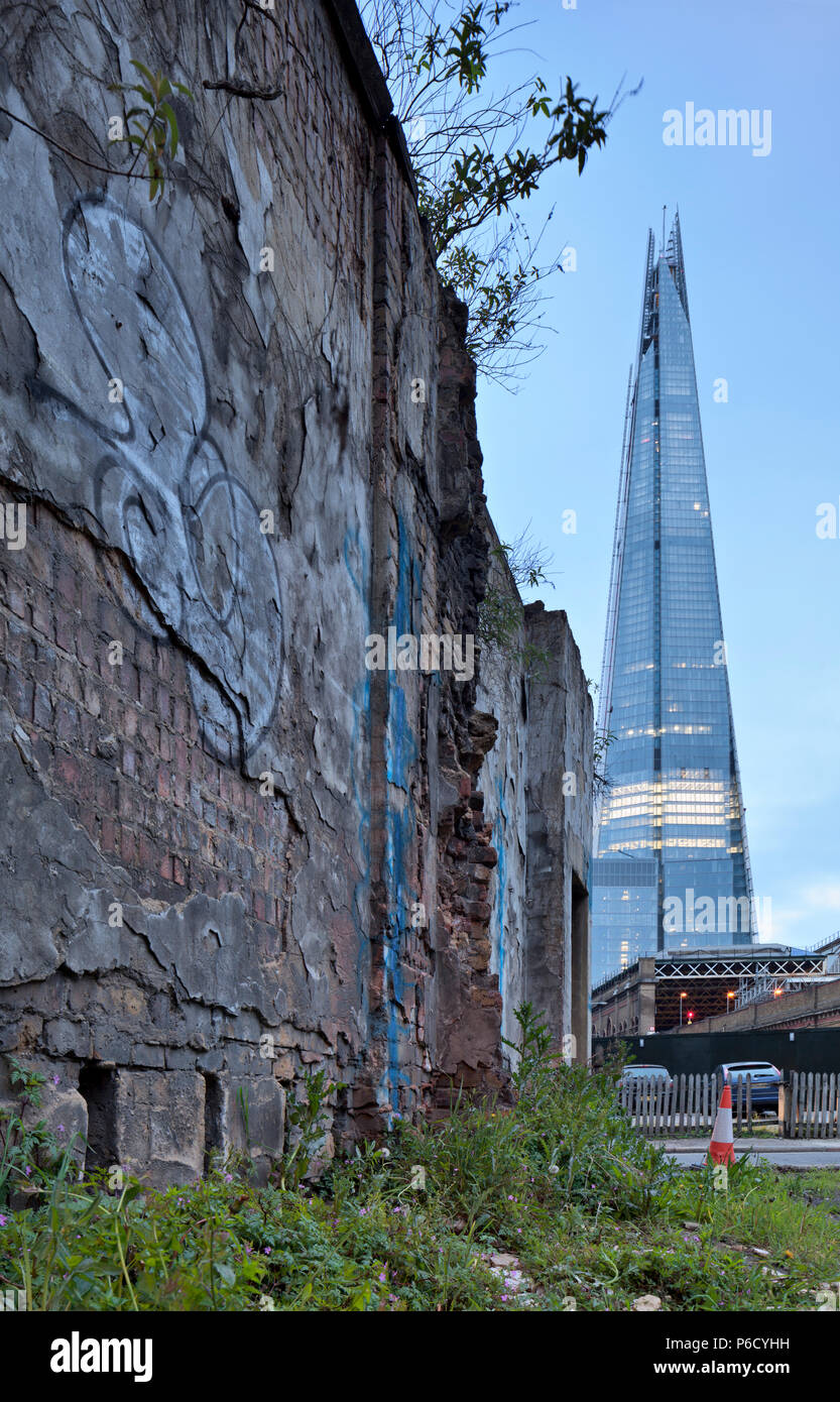 La Shard in contrasto con un vecchio muro di pietra dei magazzini sul cantiere di aceto in Southwark accanto alla stazione di London Bridge. Foto Stock