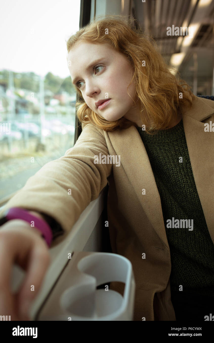 Capelli rossi giovane donna che guarda fuori dalla finestra del treno Foto Stock