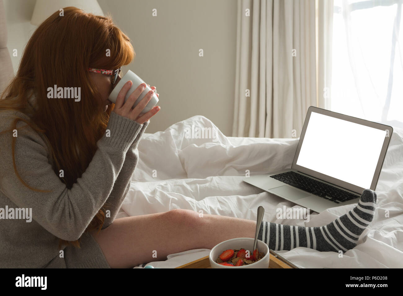 Donna con nero caffè in camera da letto Foto Stock