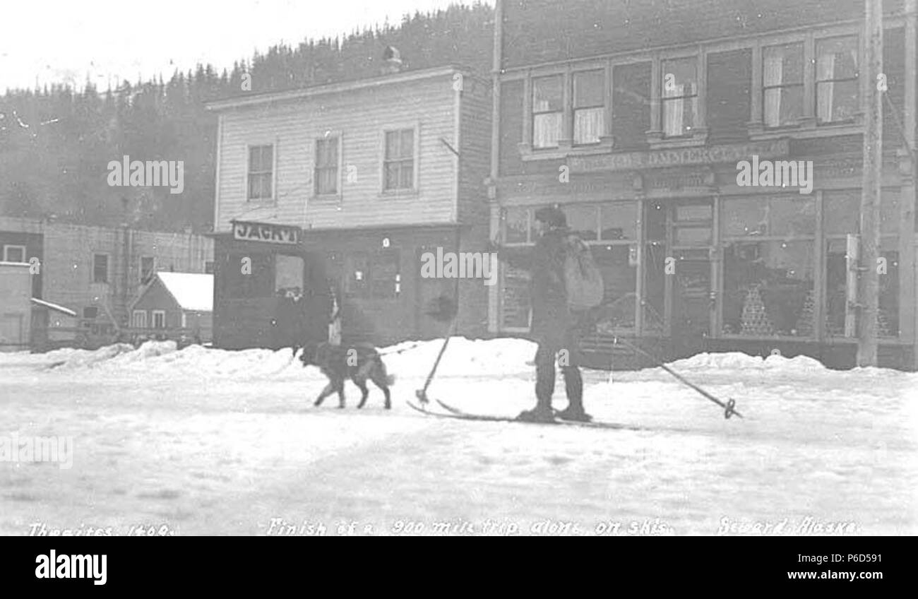 . Inglese: Uomo sugli sci essendo tirato giù street da un cane, Seward, ca. 1912 . Inglese: didascalia sull'immagine: Finitura di 900 miglia di viaggio, da soli, con gli sci. Seward, Alaska PH Coll 247.376 soggetti (LCTGM): Cani -- Alaska--Seward; gli sciatori--Alaska--Seward; Sci--Alaska--Seward; Negozi & Negozi -- Alaska--Seward; neve--Alaska--Seward; Seward (Alaska) . circa 1912 62 Uomo sugli sci essendo tirato giù street da un cane, Seward, ca 1912 THWAITES (244) Foto Stock