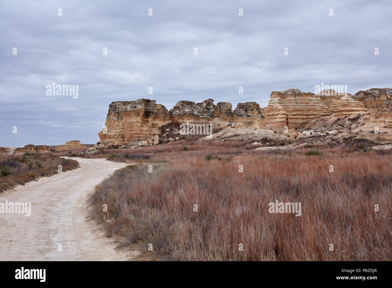 Avvolgimento su strada sterrata che conduce al castello di roccia Badlands formazioni in Kansas con pietra calcarea erosa pilastri e pile Foto Stock