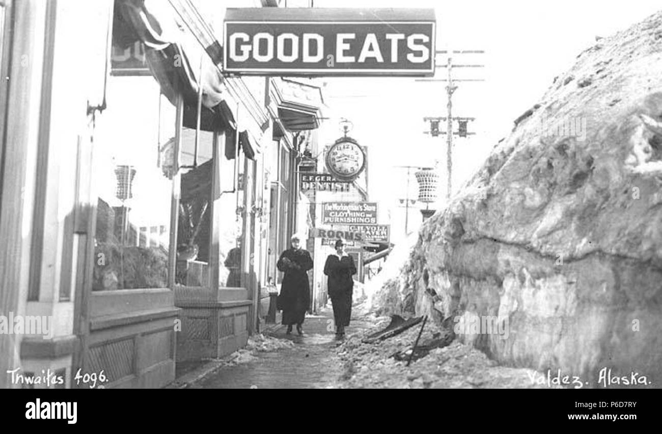 . Inglese: due donne sul marciapiede in Valdez, con neve impilate lungo il lato, ca. 1912 . Inglese: didascalia sull'immagine: Valdez in Alaska, PH Coll 247.530 Valdez si trova sulla sponda nord di Port Valdez, un profondo fiordo di acqua in Prince William Sound. Si trova a 305 miglia su strada a est di ancoraggio, e 364 miglia su strada a sud di Fairbanks. È il capolinea meridionale della Trans-Alaska oleodotto. Il porto di Valdez fu nominato nel 1790 da Don Salvador Fidalgo per la celebre spagnolo addetto navale Antonio Valdés y Basan. Grazie alla sua eccellente ice-free port, una città si è sviluppata nel 1898 come un punto dello sbarco per uomini s Foto Stock