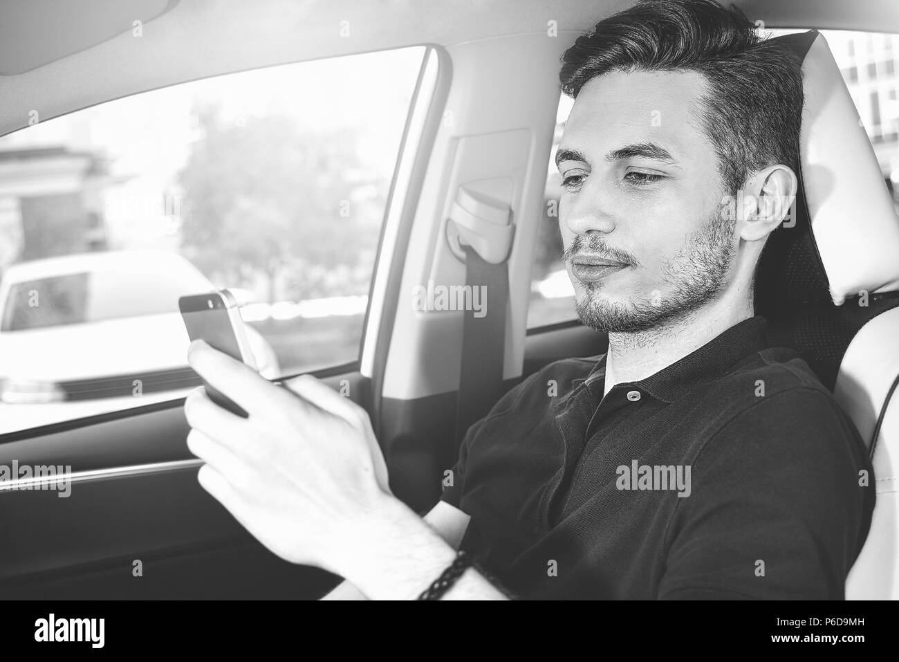 Imprenditore texting sul suo telefono cellulare durante la guida. Driver pericolose. Foto Stock