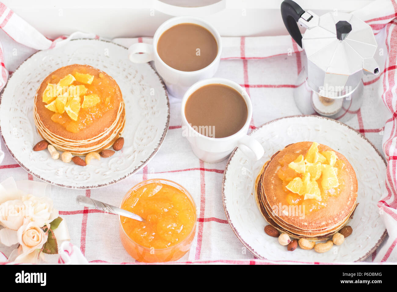 Tradizionale e romantica la prima colazione per due in un vassoio. American pancake con marmellata di arancia e i dadi sulle piastre di vintage e bianco 2 tazze di caffè con me italiano Foto Stock